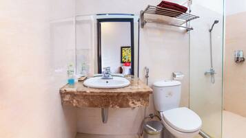 A bathroom with a marble sink, a toilet, a glass shower enclosure, and a towel rack.