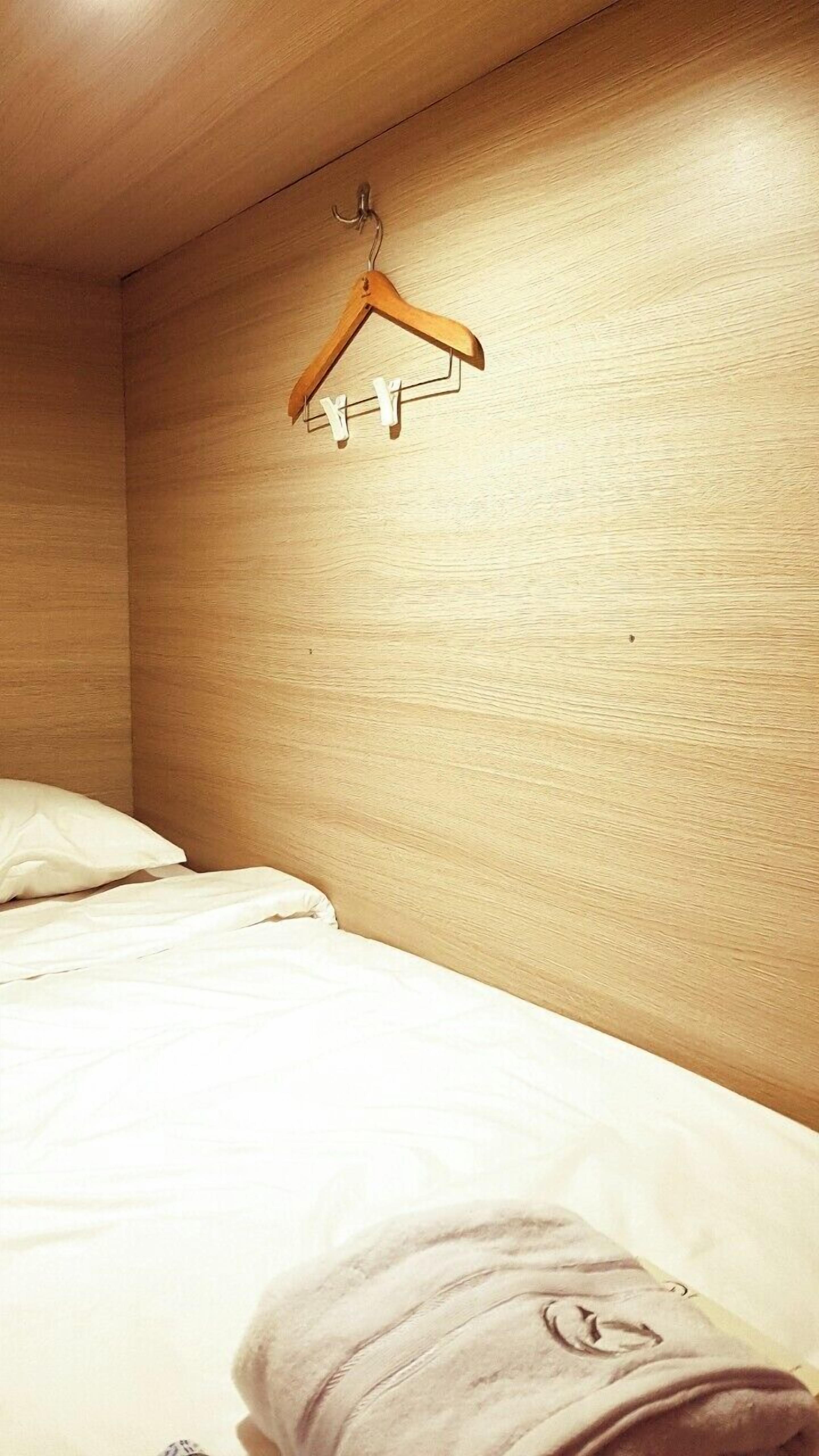 Una camera d'albergo con una testiera in legno, un appendiabiti di legno con delle lettere e un letto rifatto.