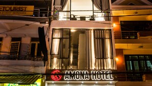 A multi-story hotel with a prominent sign for "Amona Hotel" and a neon sign above the entrance. - Amona Hotel - Hostel (Hue)