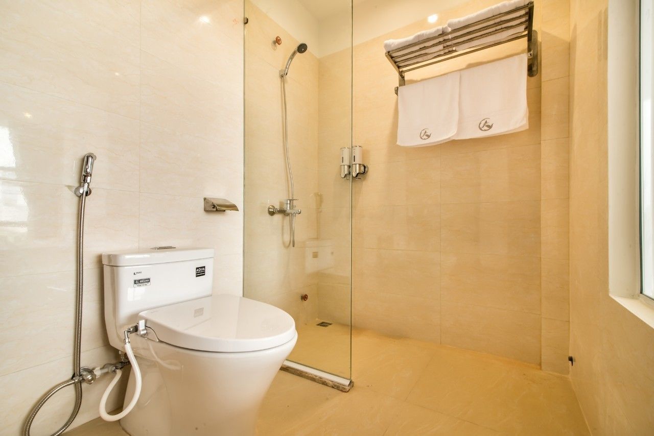 A modern bathroom with a glass-enclosed shower, a toilet, and a towel rack.