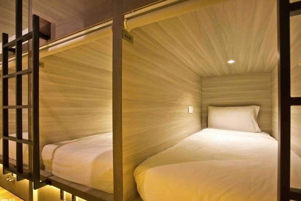 A room with two bunk beds, wooden walls, and a ceiling with a recessed light.