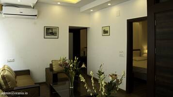 A hotel lobby with a sofa, a table with flowers, a ceiling fan, and an air conditioning unit.