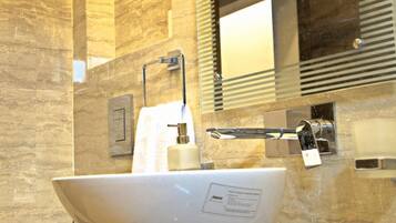 Une salle de bain moderne avec un grand lavabo sur pied blanc, un miroir et un distributeur de serviettes.