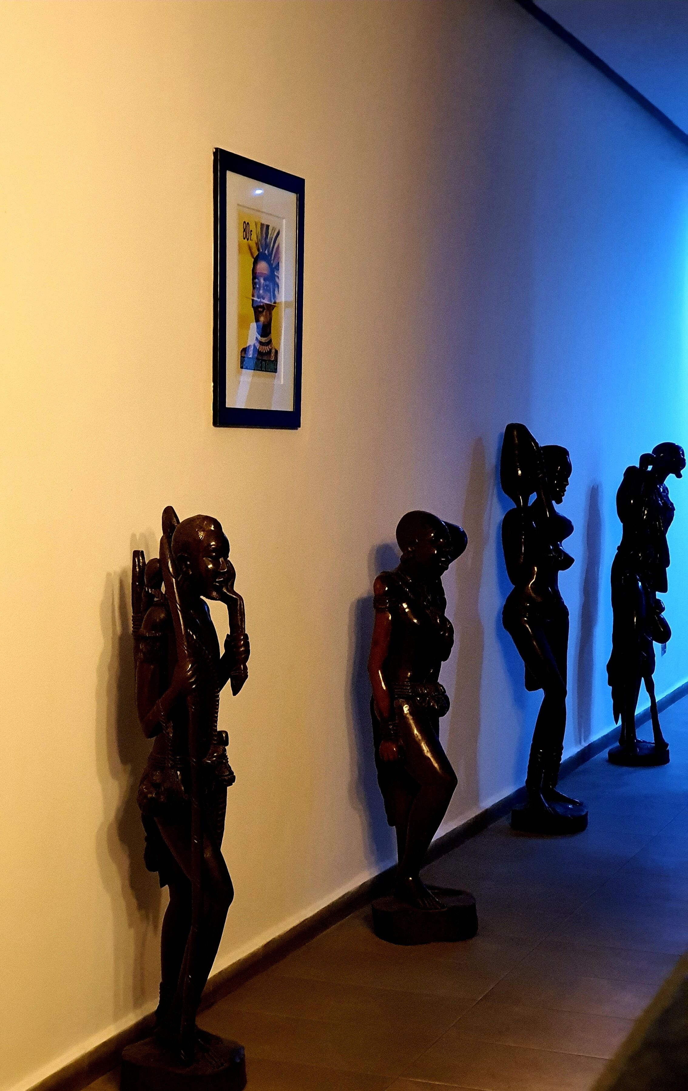 A hallway with a series of sculptures on the wall and a framed picture above them.