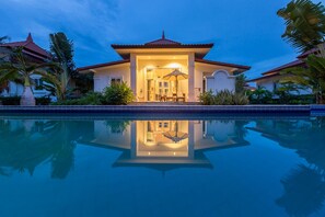 Una casa moderna con piscina, rodeada de plantas tropicales.