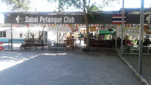 Un club deportivo llamado 'Sabai Petanque Club' con asientos al aire libre y una zona cubierta.