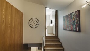 Una escalera con peldaños de madera y un reloj fijado a la pared.