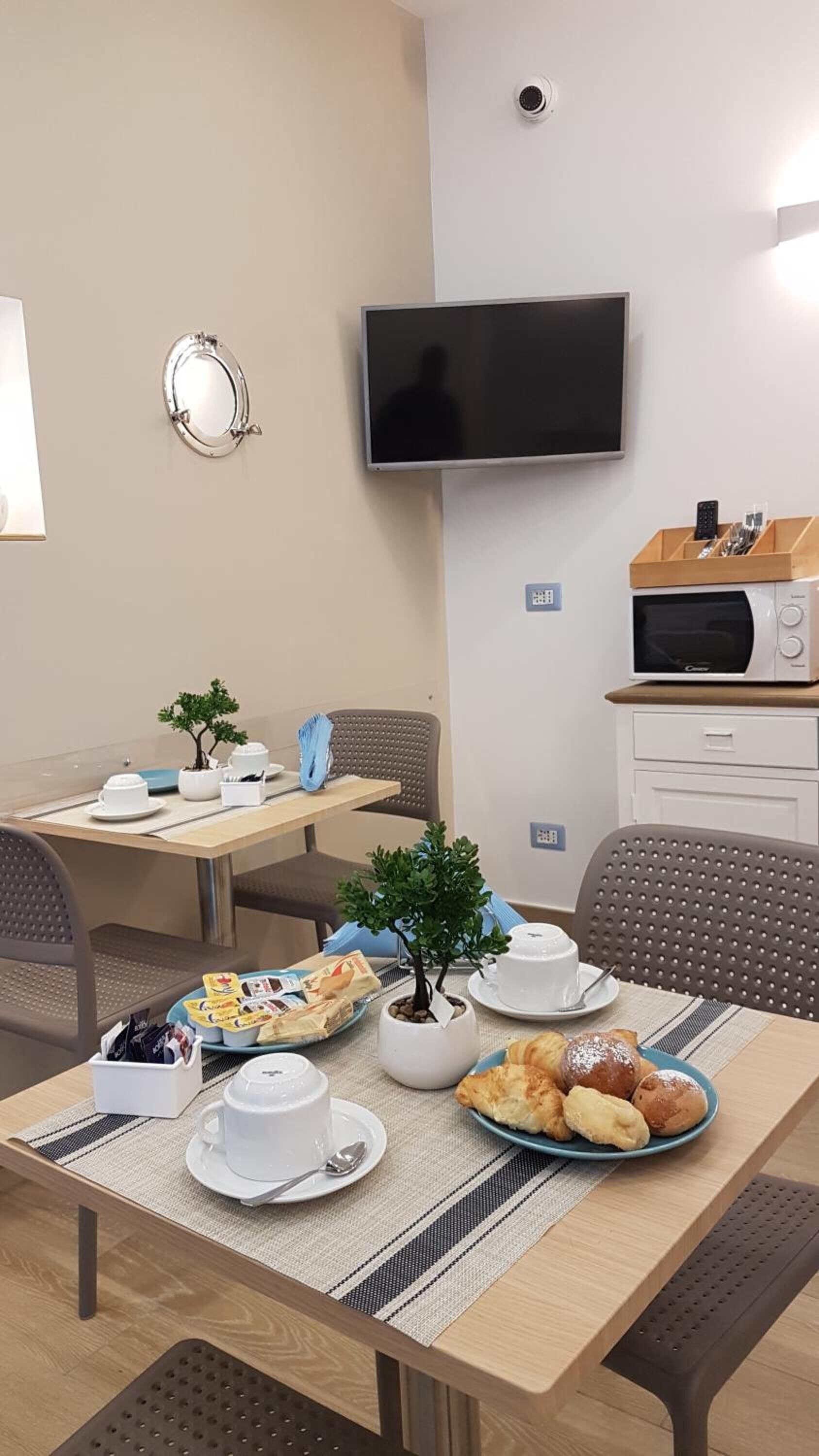 A dining area with a table set for breakfast, including pastries and a small potted plant.