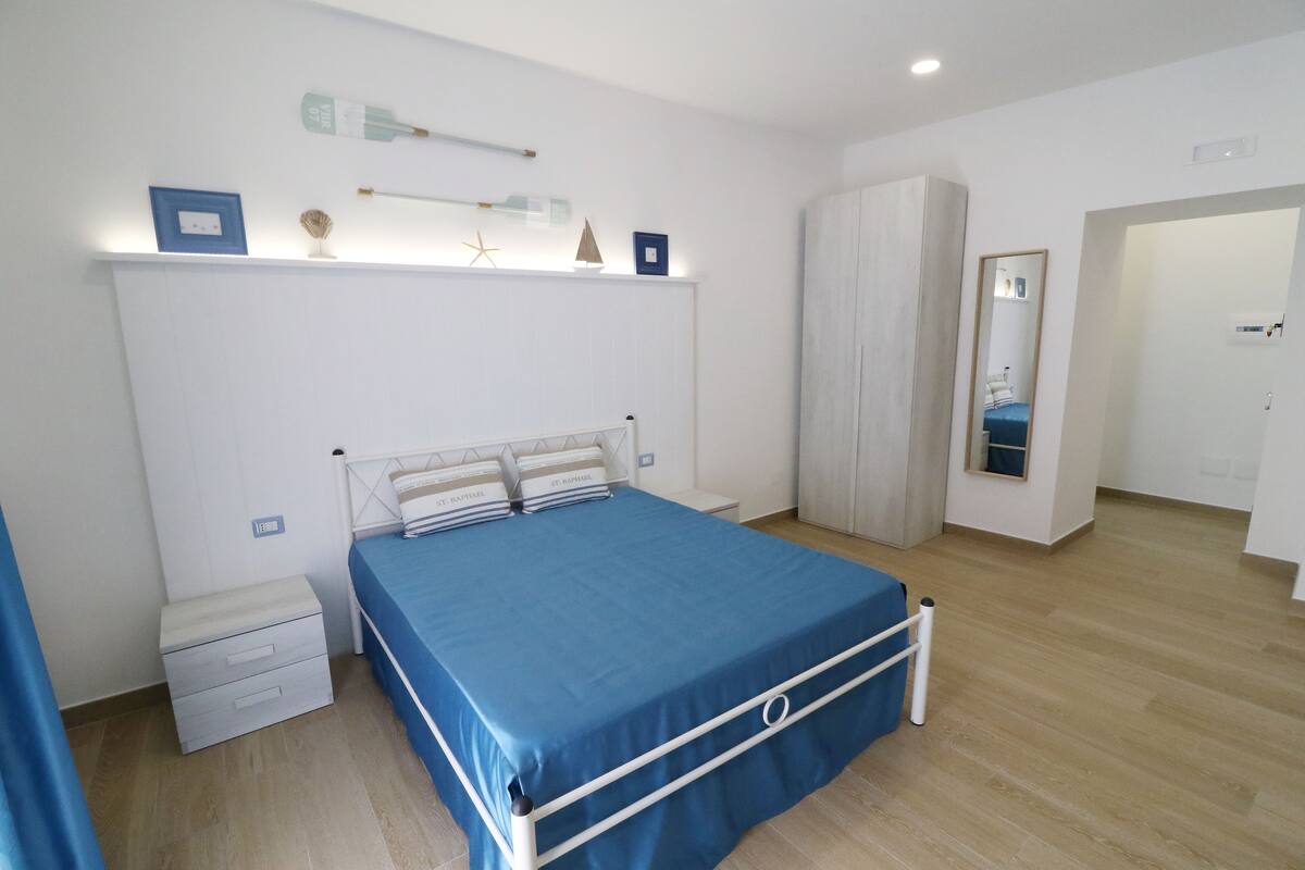 A bedroom with a bed, bedside tables, a wardrobe, and a mirror.