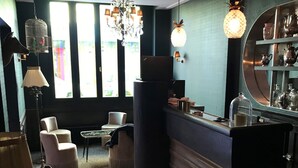 Un área de bar moderna con mostrador, asientos y una araña.