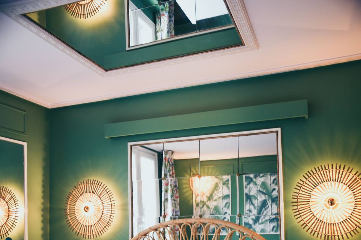 A room with a large bed, green walls, and decorative wall lights.