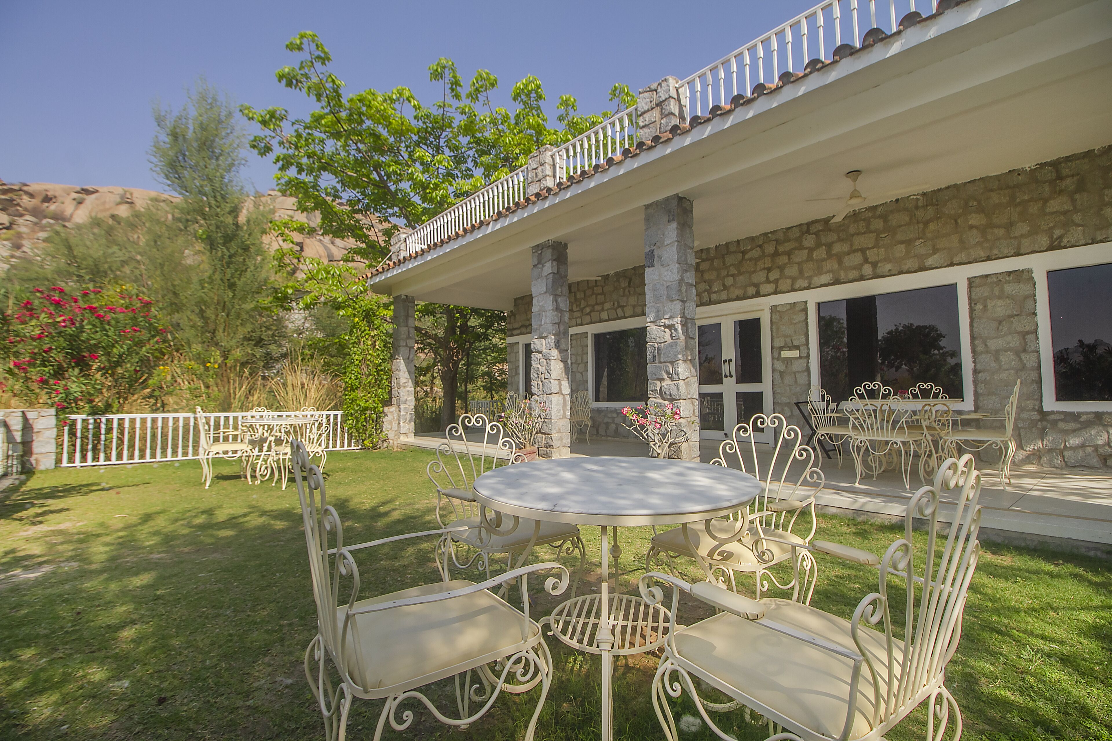A patio with outdoor furniture, stone columns, and a stone building with large windows.