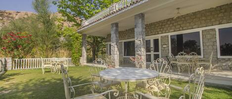 A patio with outdoor furniture, stone columns, and a stone building with large windows.