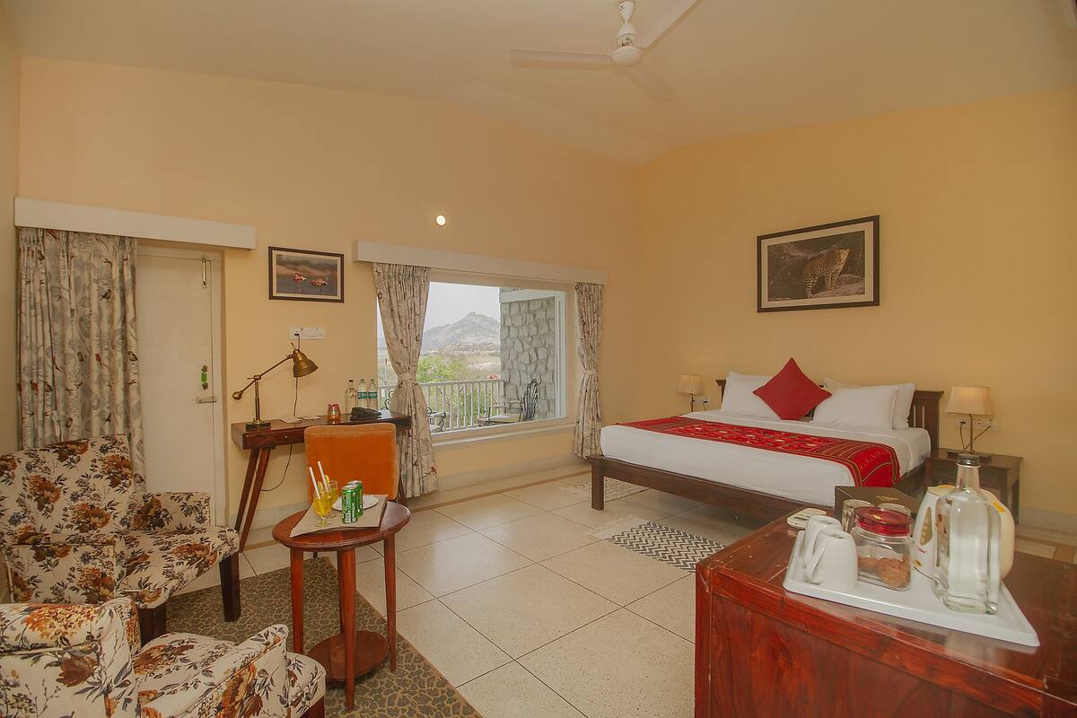 Ein Hotelzimmer mit Bett, Schreibtisch, Stuhl und Blick ins Freie.