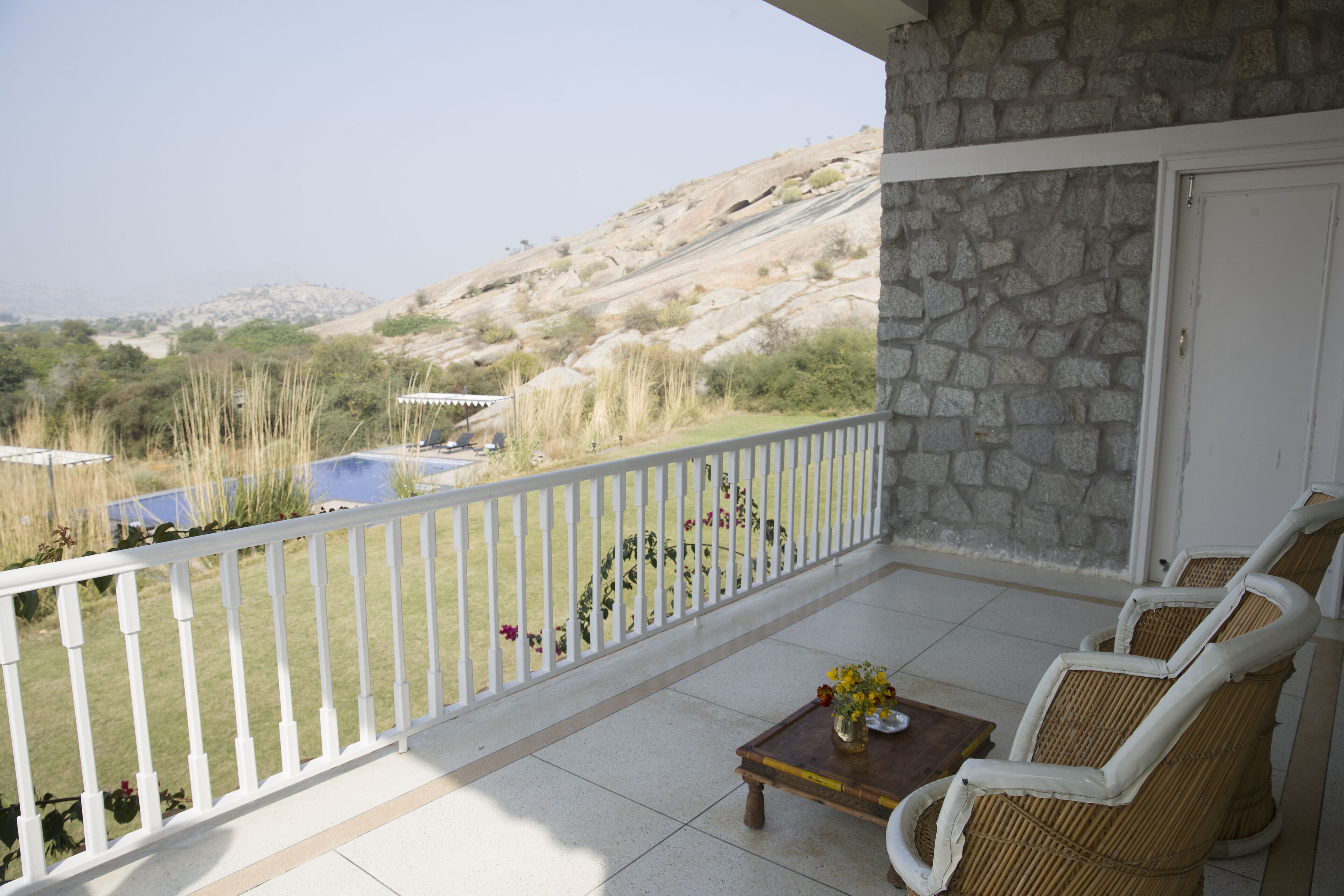 A balcony with a stone wall, white railing, and wicker chairs.