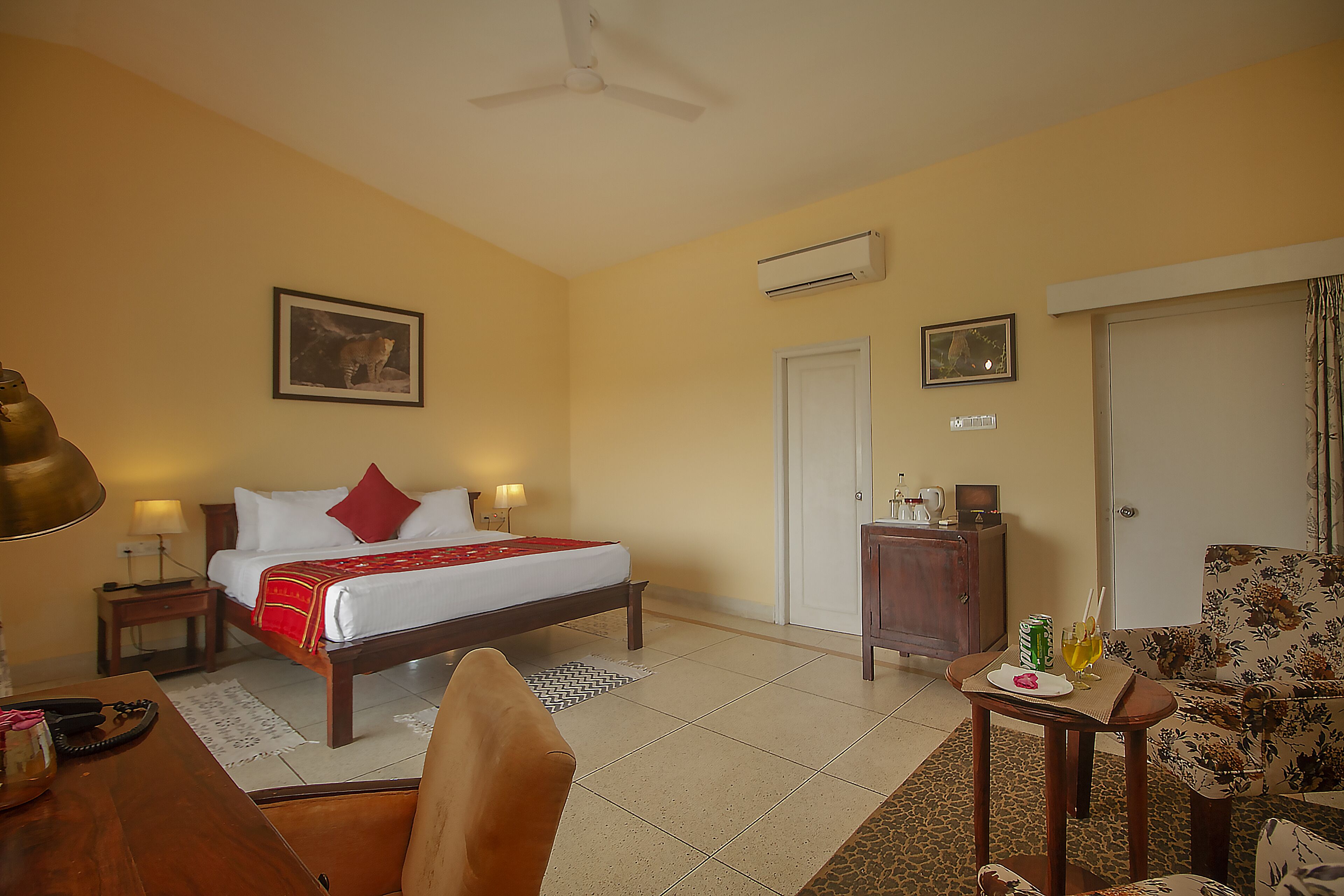 A hotel room with a bed, a desk, a chair, a sofa, a wardrobe, and an air conditioning unit.