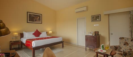 Ett hotellrum med en säng, ett skrivbord, en stol, en soffa, en garderob och en luftkonditioneringsanläggning.