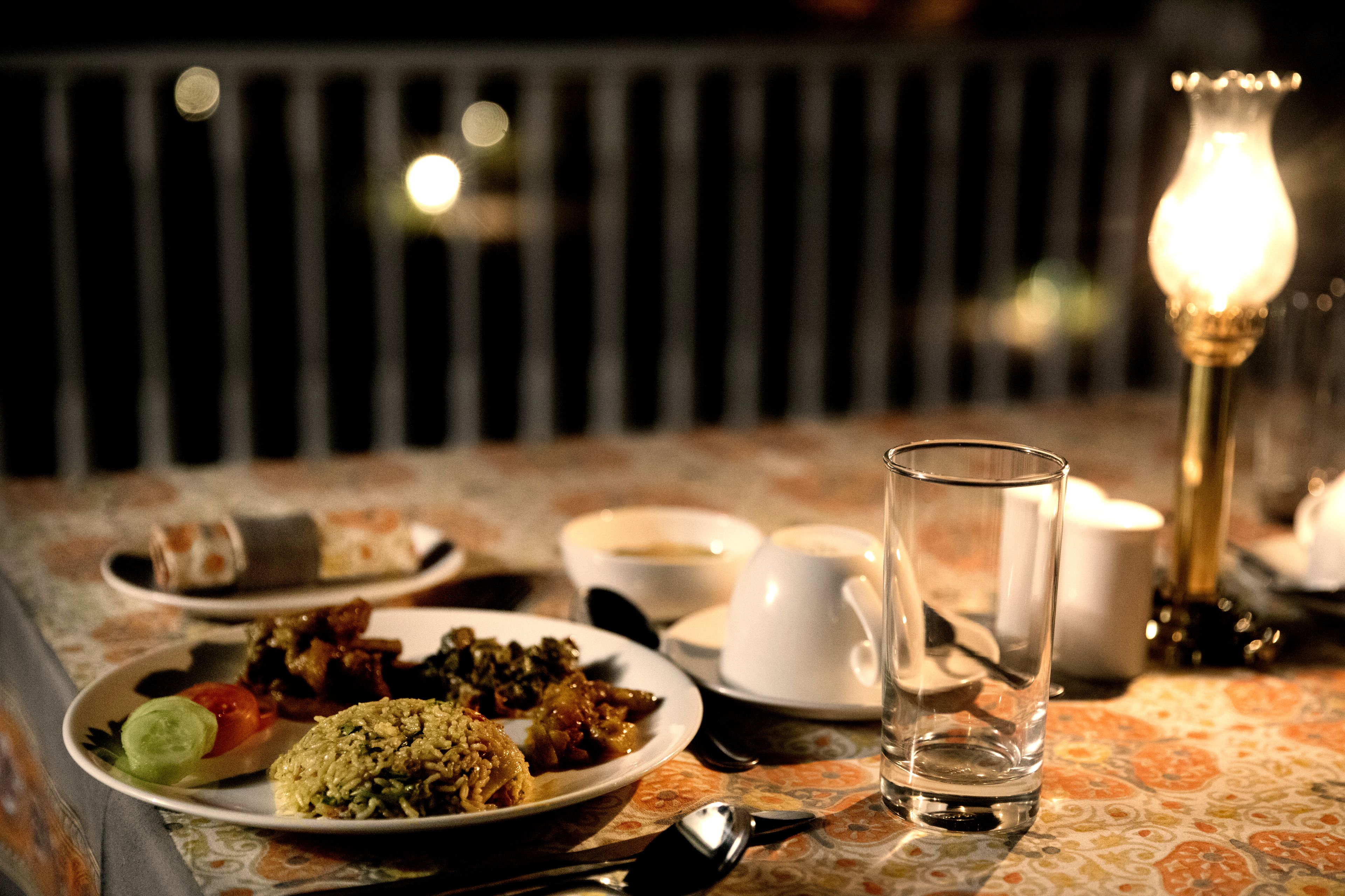 A dining table with plates of food, a glass, and a candle.