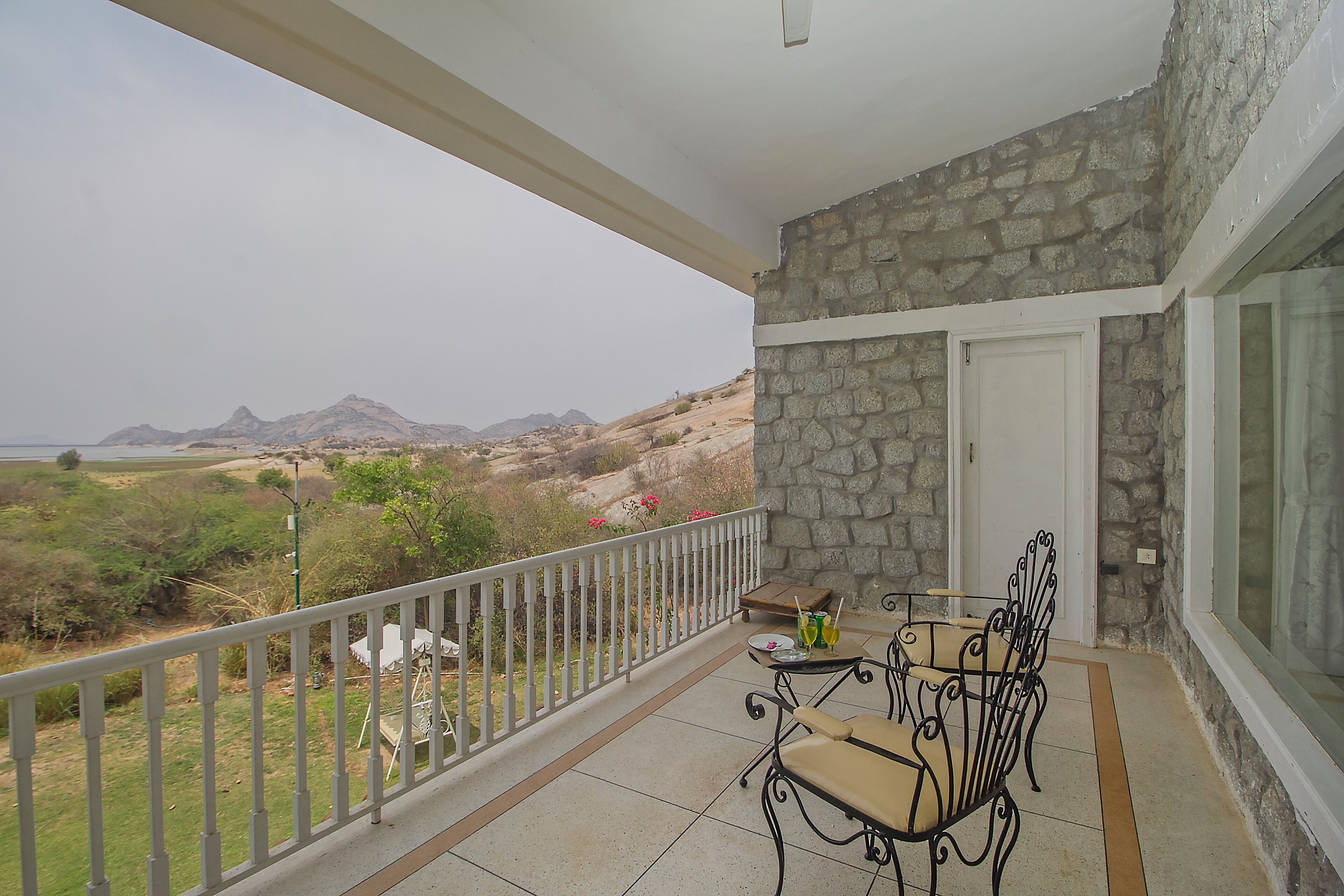 A balcony with a stone wall, a white door, and a view of a mountainous landscape.