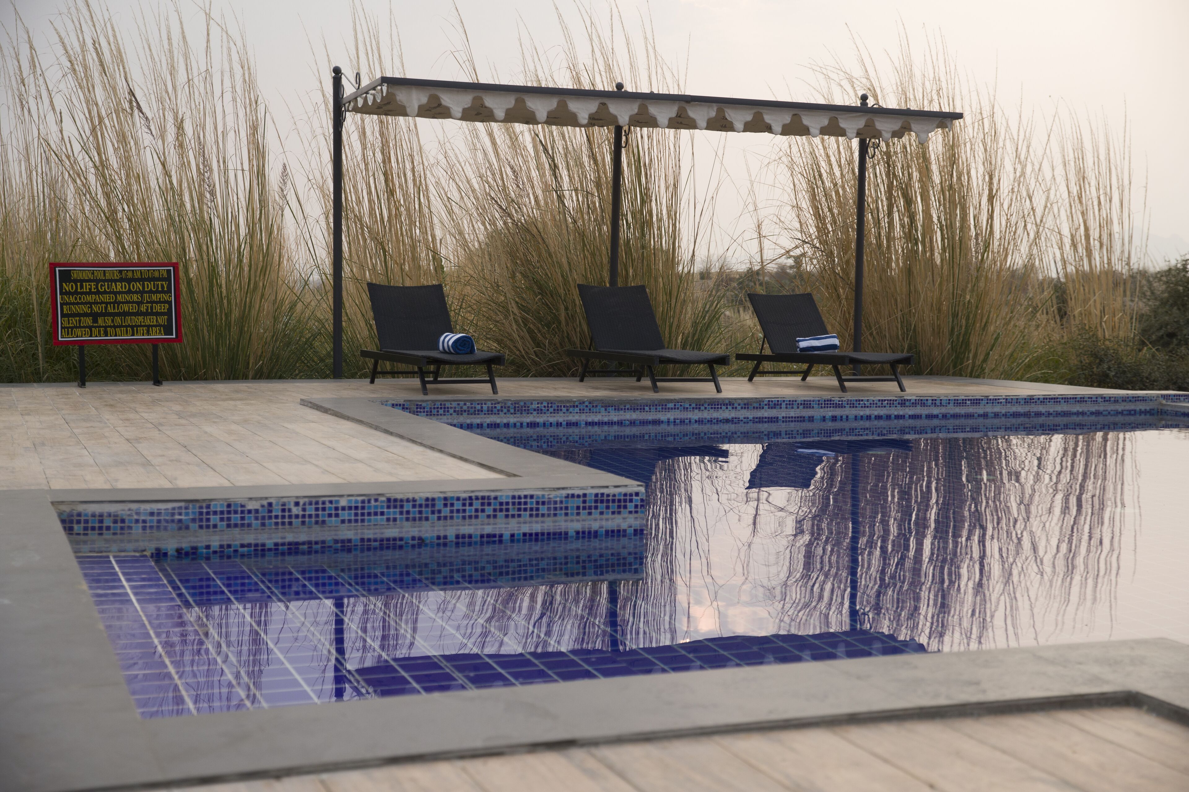 A swimming pool with lounge chairs and a covered area.