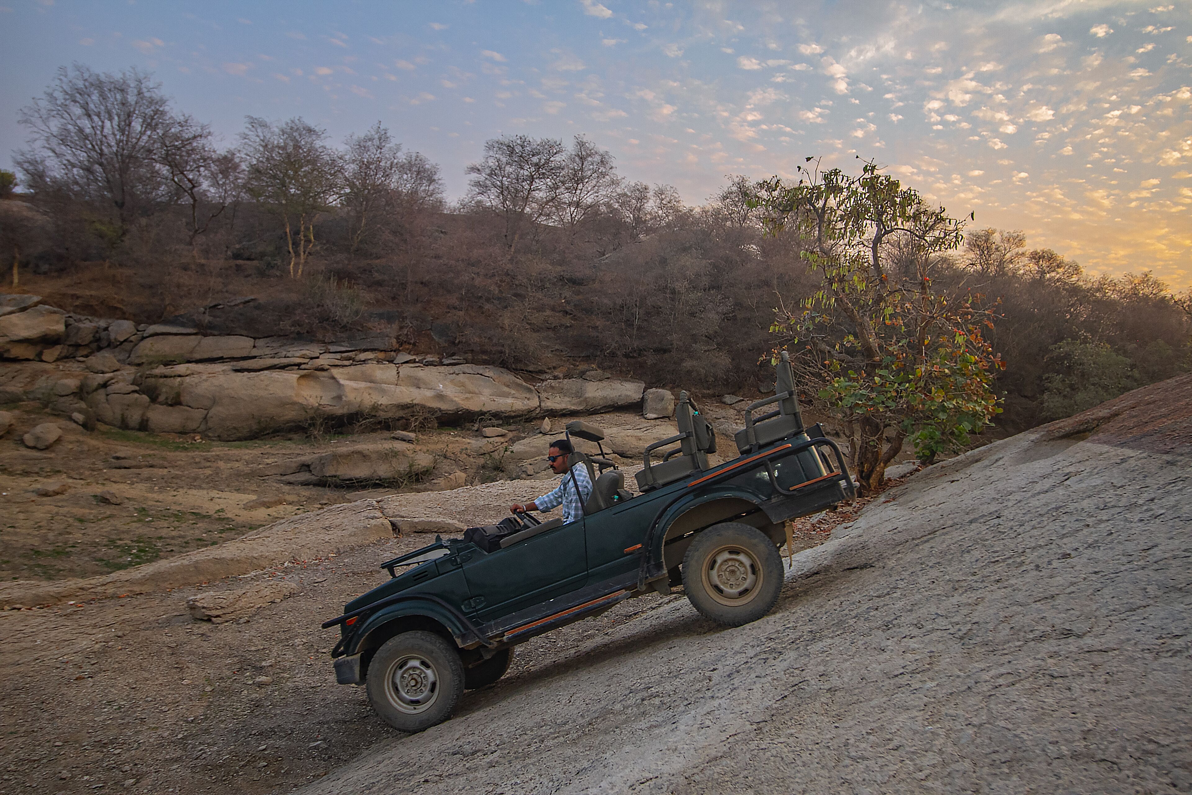A convertible car driving on a dirt road.