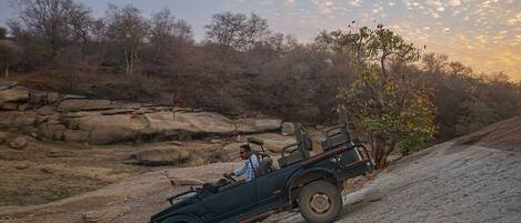 A convertible car driving on a dirt road.