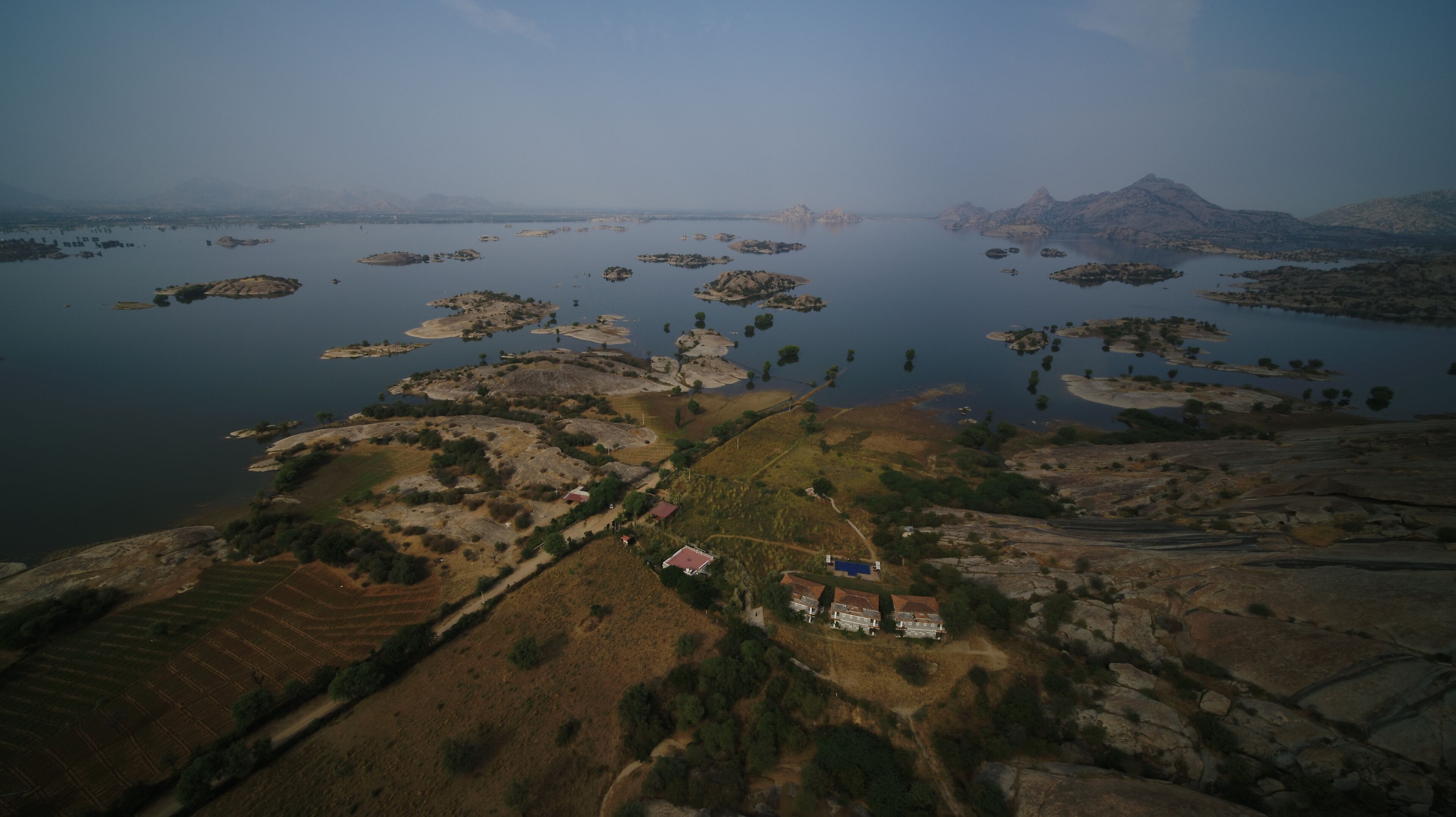 Vista aérea de una zona costera con islas dispersas, terreno rocoso y algunos edificios.