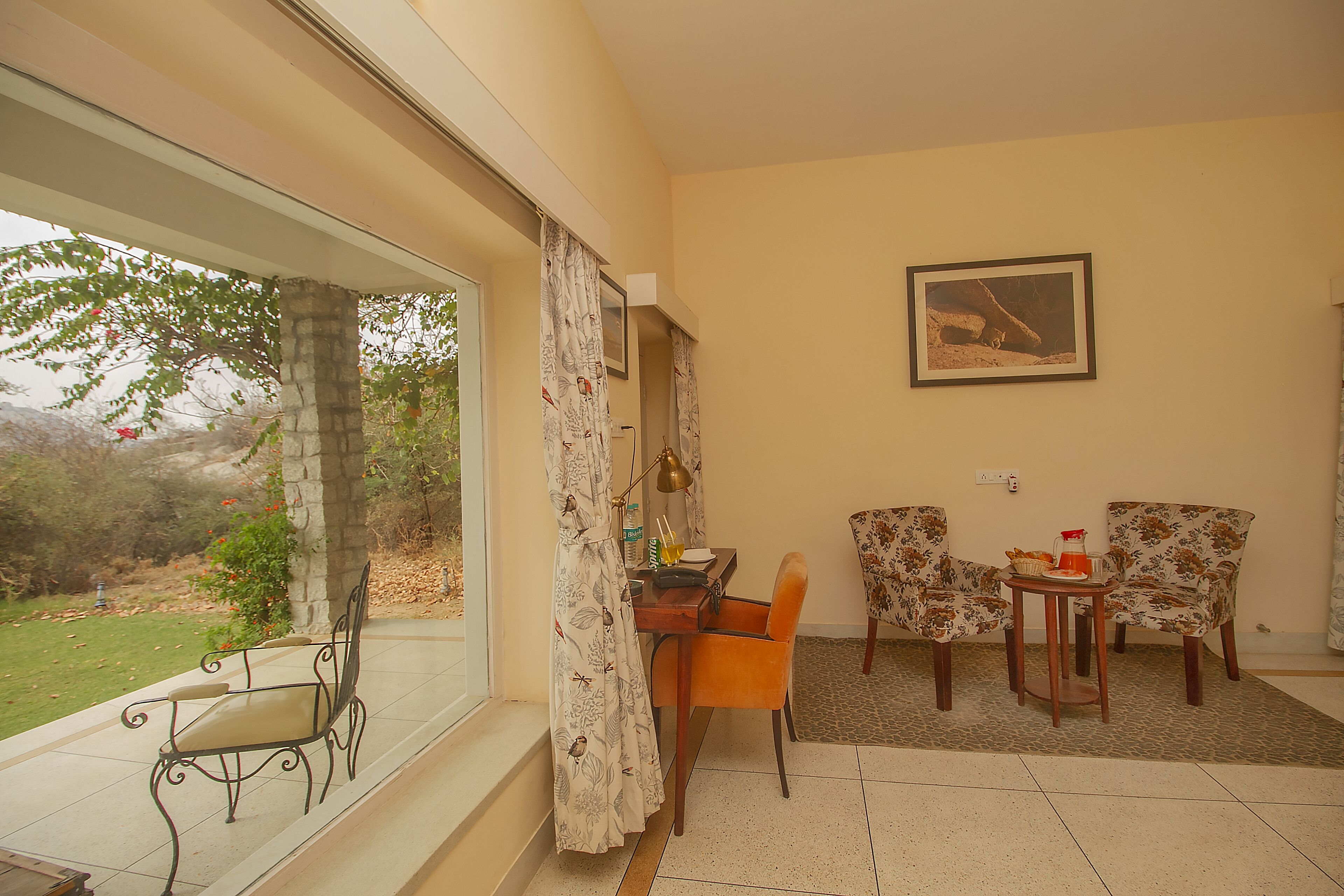 A room with a dining table, two chairs, a small side table, and a window with curtains.