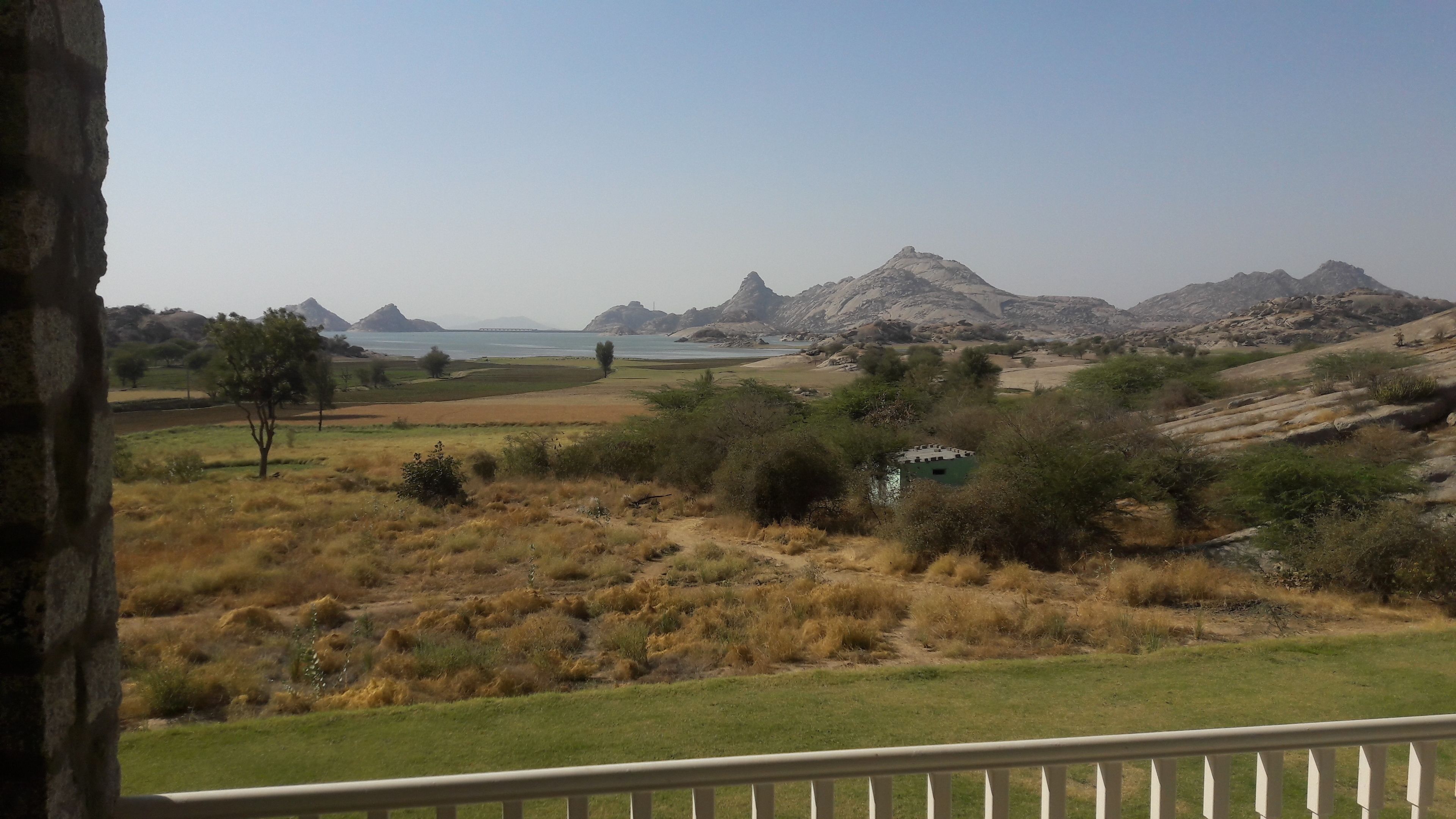 A view of a mountainous landscape with a body of water and a small building in the foreground.