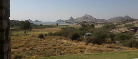 A view of a mountainous landscape with a body of water and a small building in the foreground.