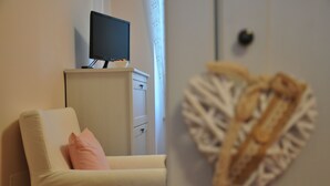A room with a white sofa, a television on a cabinet, and a decorative wall piece. - Dimora Paolina (Baschi)