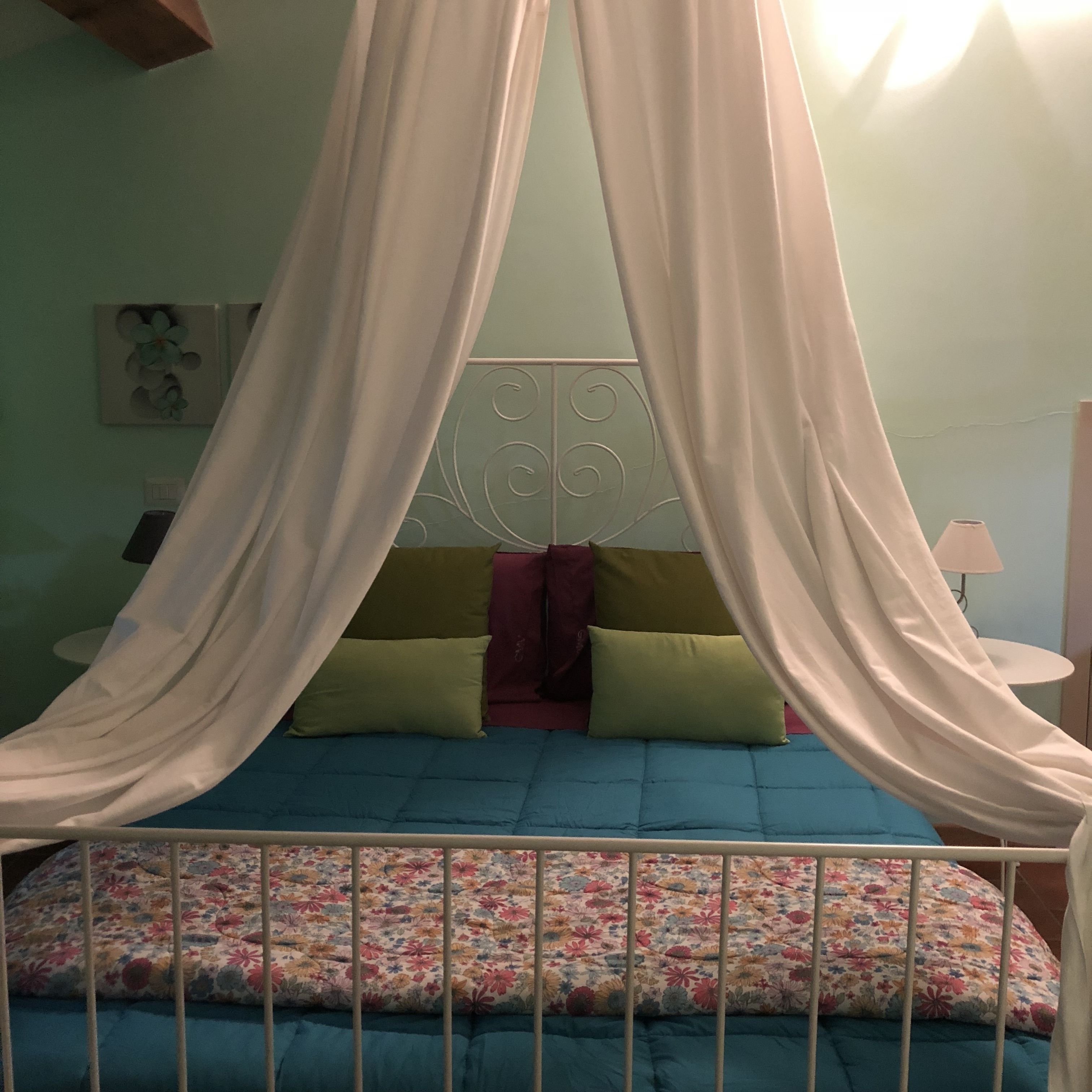 A bed with a canopy, a headboard, and a floral bedspread.