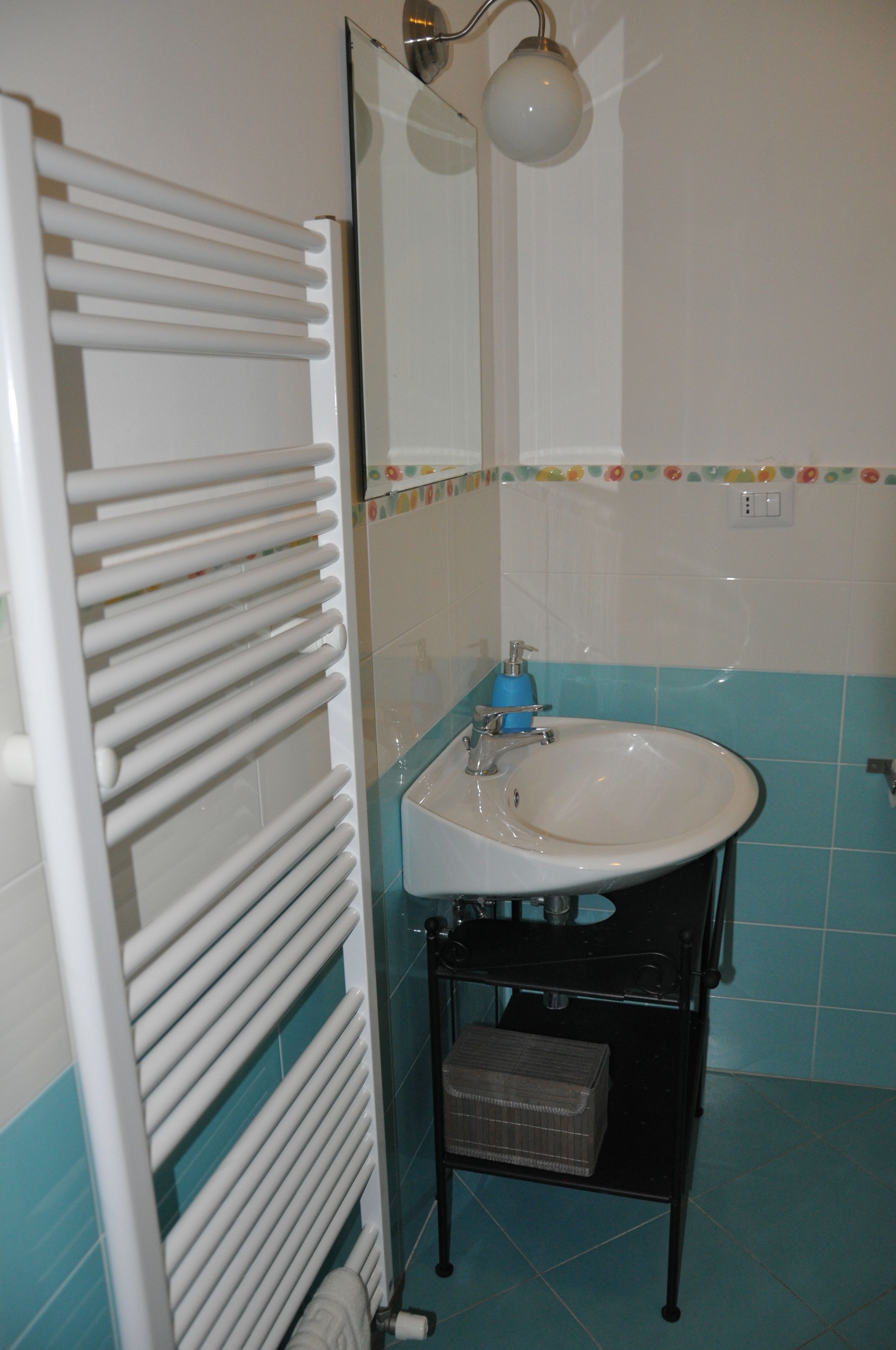 Une salle de bain avec un radiateur blanc, un lavabo et un miroir.