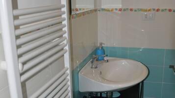 Une salle de bain avec un radiateur blanc, un lavabo et un miroir.