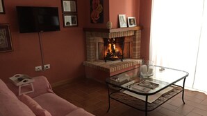 A living room with a fireplace, a flat-screen TV, a pink sofa, and a glass coffee table. - Dimora Paolina (Baschi)