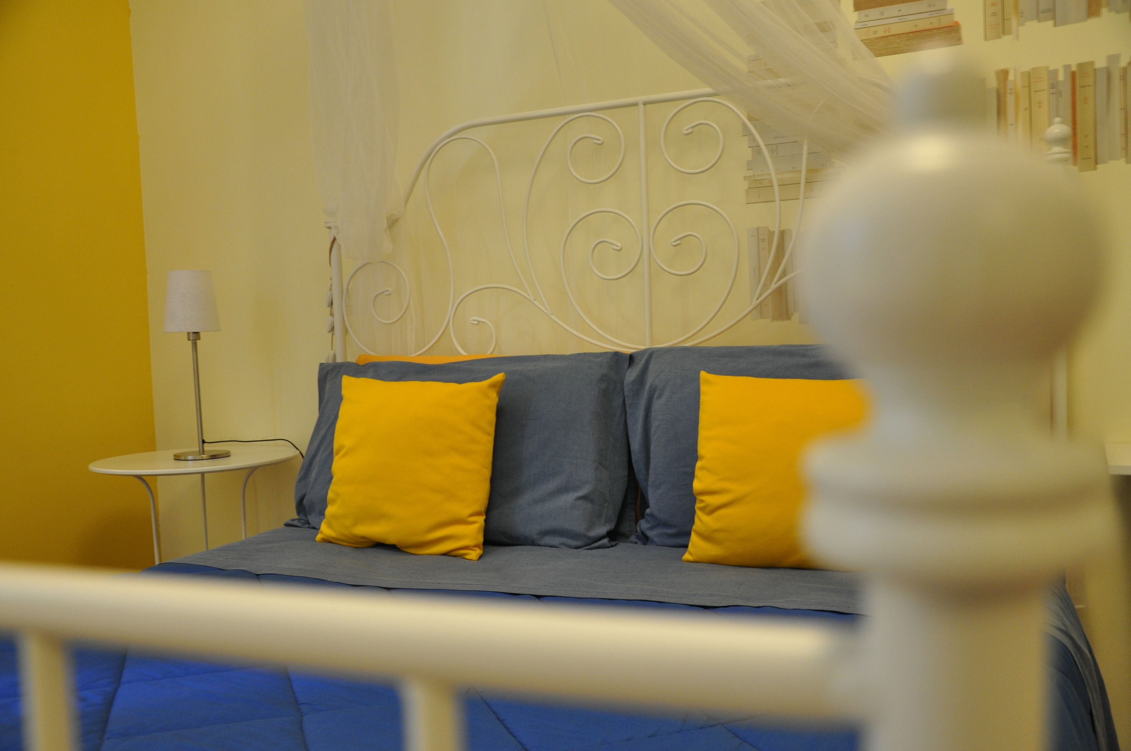 A bed with a metal headboard, two pillows, and a blue bedspread.
