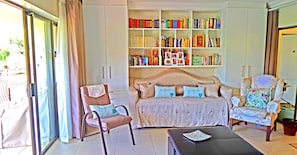 A living room with a sofa, two armchairs, a coffee table, and a bookshelf filled with books.