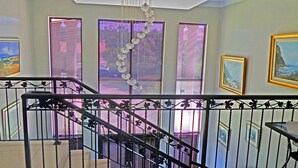 A staircase with a metal railing, leading to a landing with three windows with blinds. - Jeanette's Villa at Westlake (Hartbeespoort)