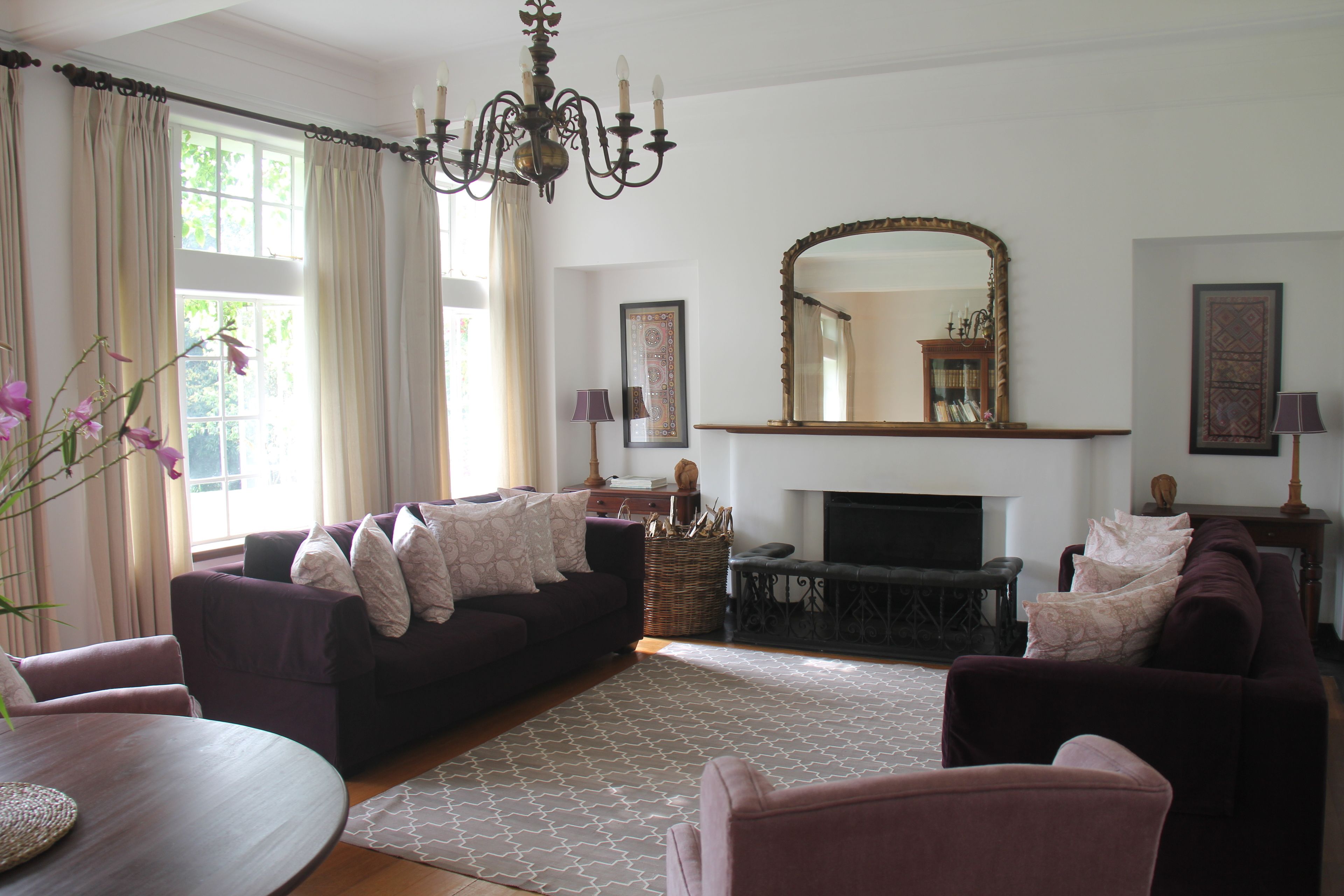 A living room with a fireplace, two sofas, a coffee table, and a chandelier.