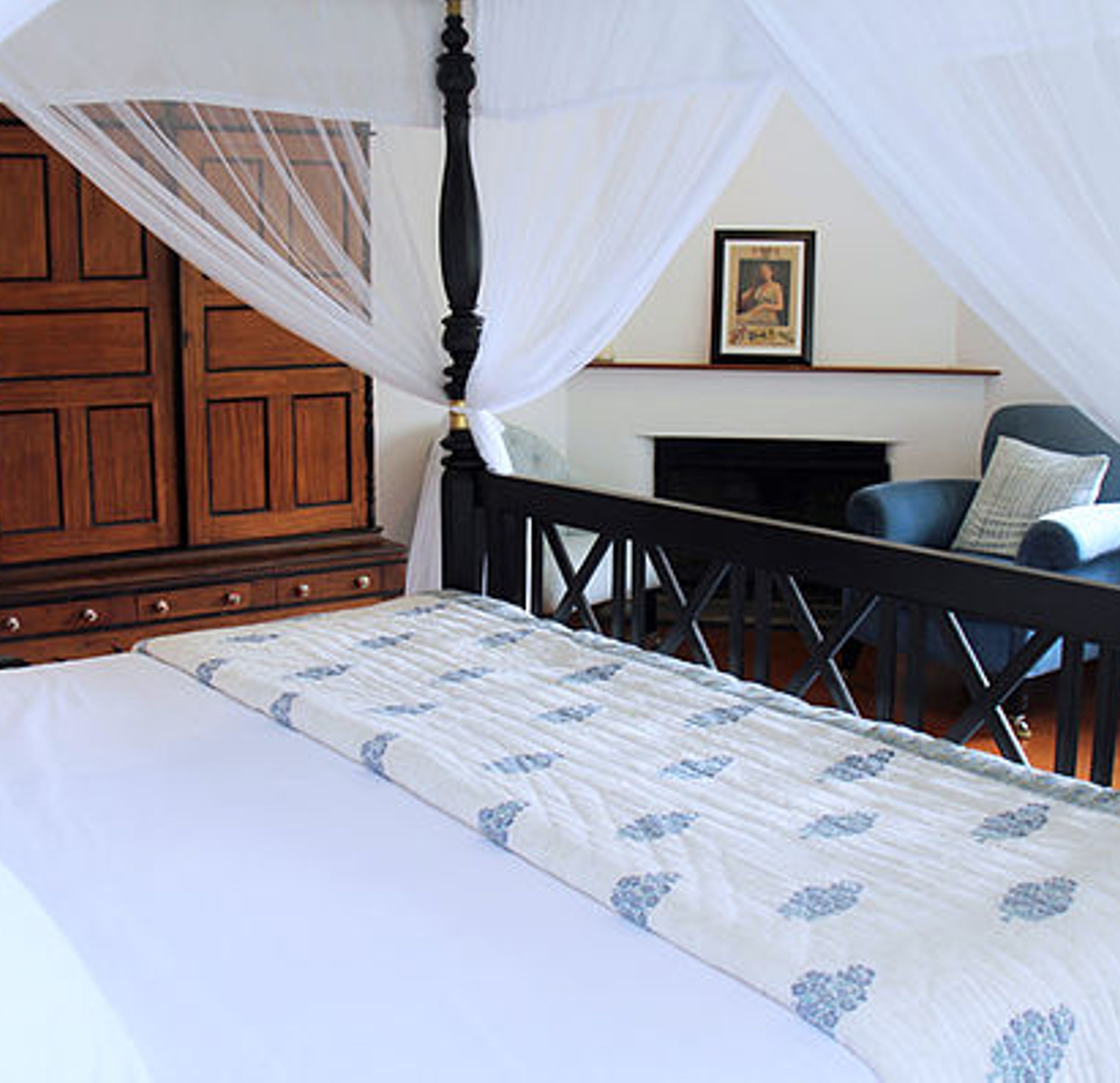 Un dormitorio con cama con dosel, un armario de madera y una silla.