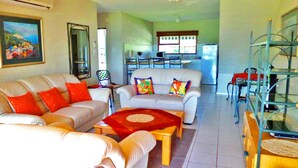 A living room with a sofa set, a coffee table, and a dining area with chairs and a table. - Key West Condo Apartment (Hartbeespoort)