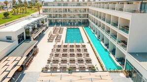 Un hotel con una amplia piscina cubierta, varios balcones y una terraza en la azotea.