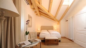 Een slaapkamer met een bed, nachtkastjes, een stoel, een klein tafeltje met een boek en een bloempot.