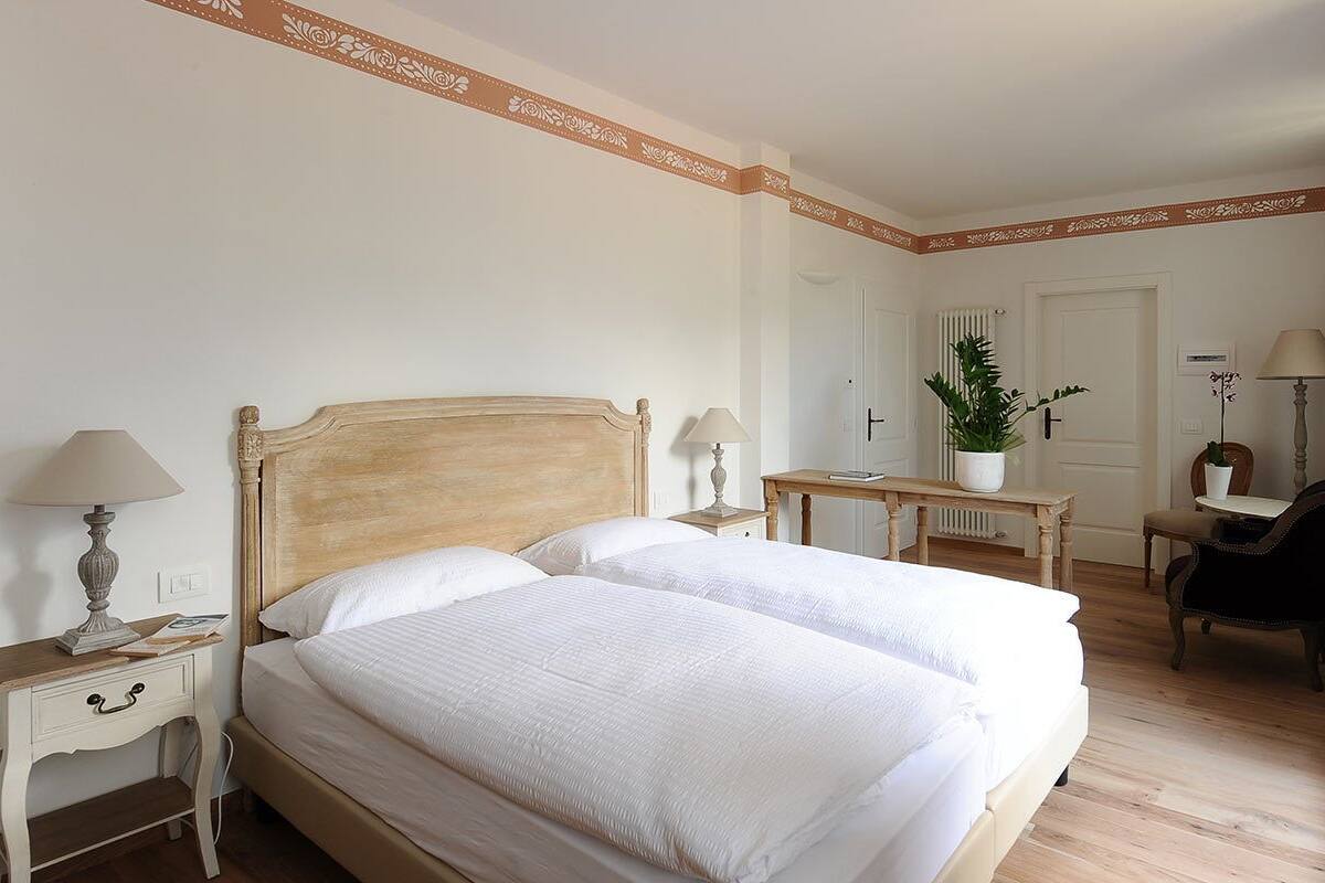 Una habitación de hotel ordenada con una cama grande, mesitas de noche, un escritorio y una silla.