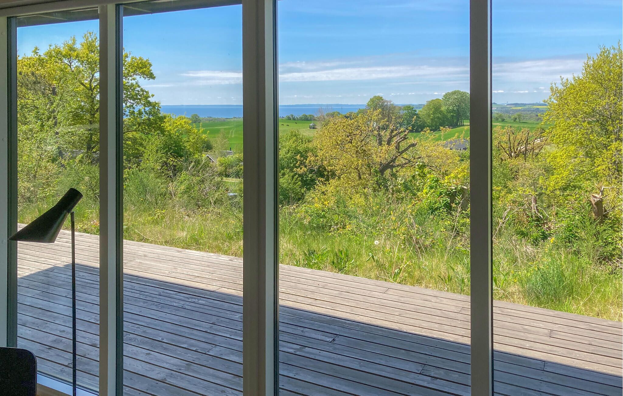 A wooden deck with a view of a green landscape and a body of water.