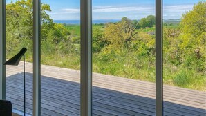 A wooden deck with a view of a green landscape and a body of water. - Nice home in Knebel with house sea view (Knebel)