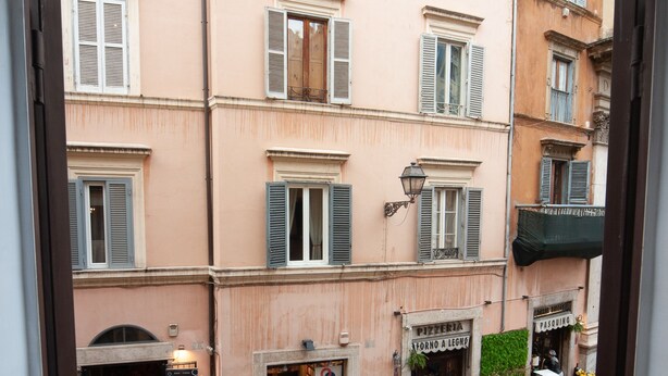 Une vue depuis une fenêtre d’un immeuble abritant de nombreux commerces, donnant sur une rue pavée.