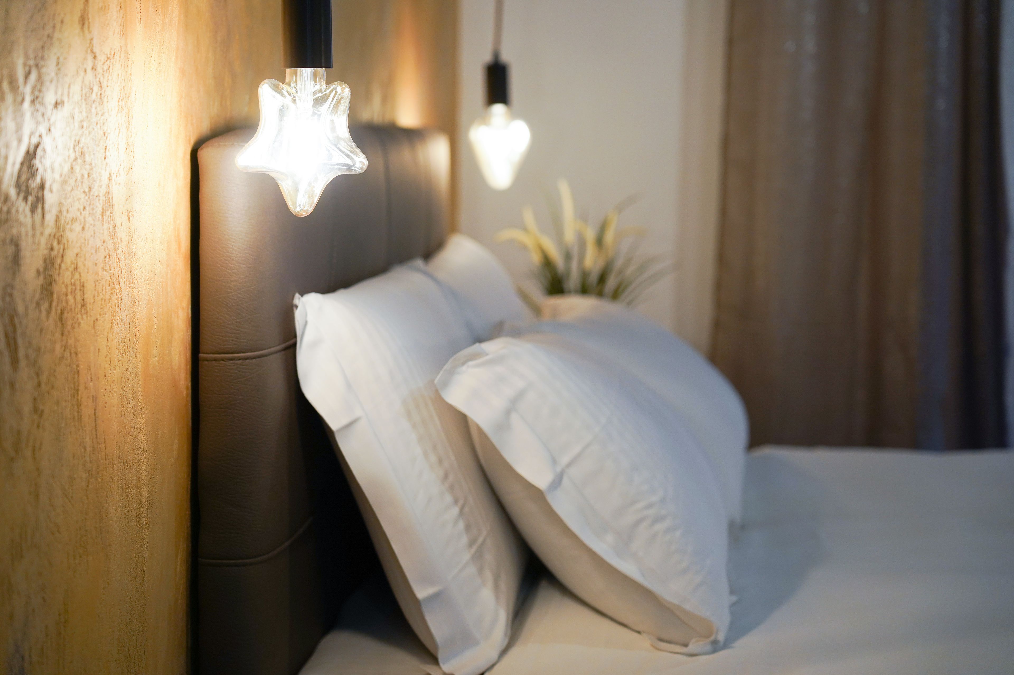 Ein Schlafzimmer mit Kopfteil, zwei Kissen und zwei Pendelleuchten.
