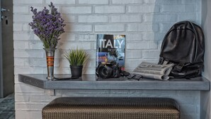 Un comptoir d’accueil avec un livre intitulé « ITALIE, par citalia », un appareil photo, un sac à dos noir et une plante en pot.