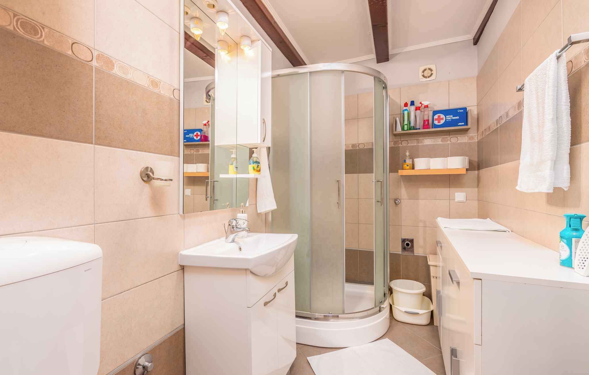 Un baño moderno con cabina de ducha de vidrio, lavabo blanco y tocador con estantes.